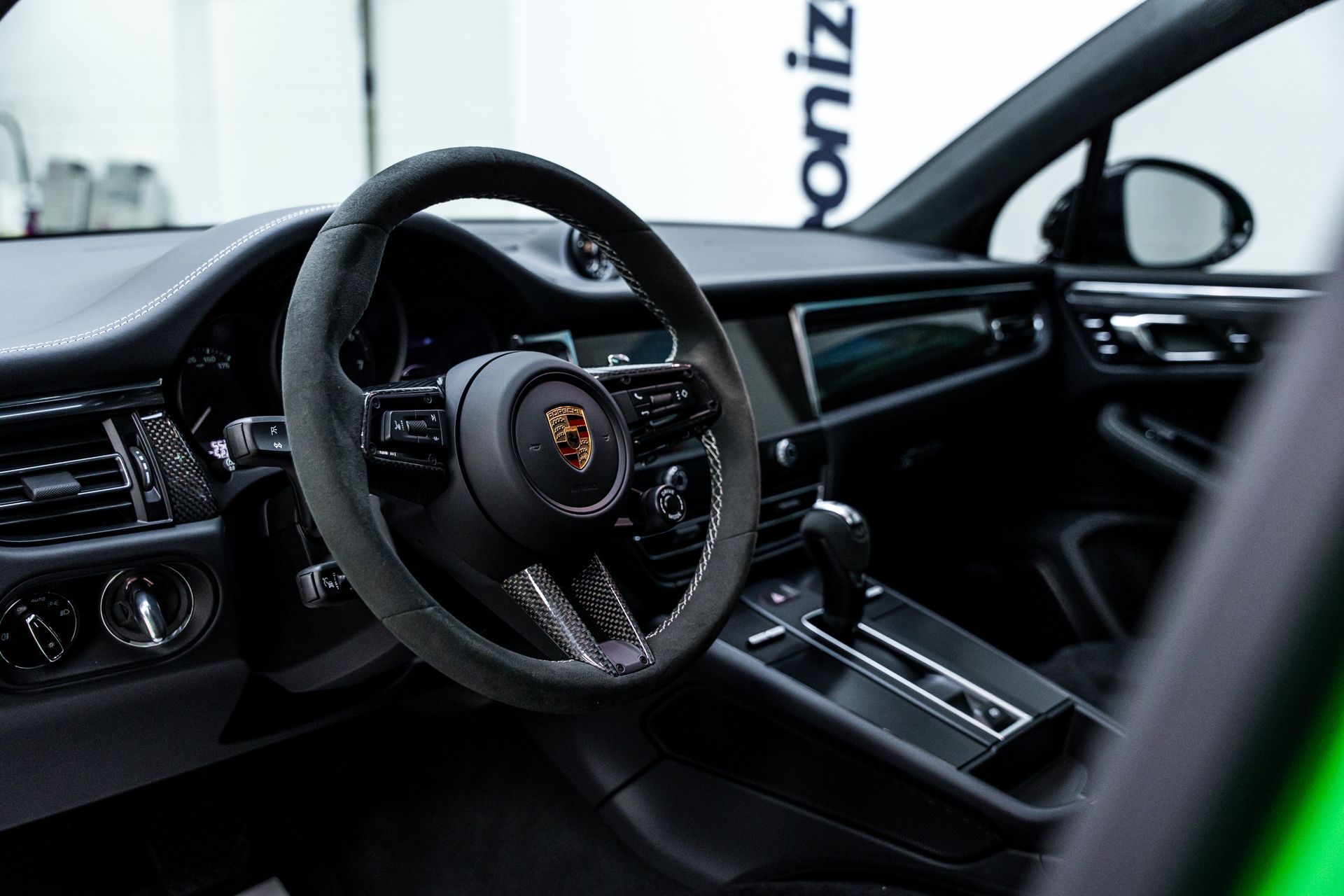 Interior of a black Porsche Macan, showing the steering wheel and dashboard details.