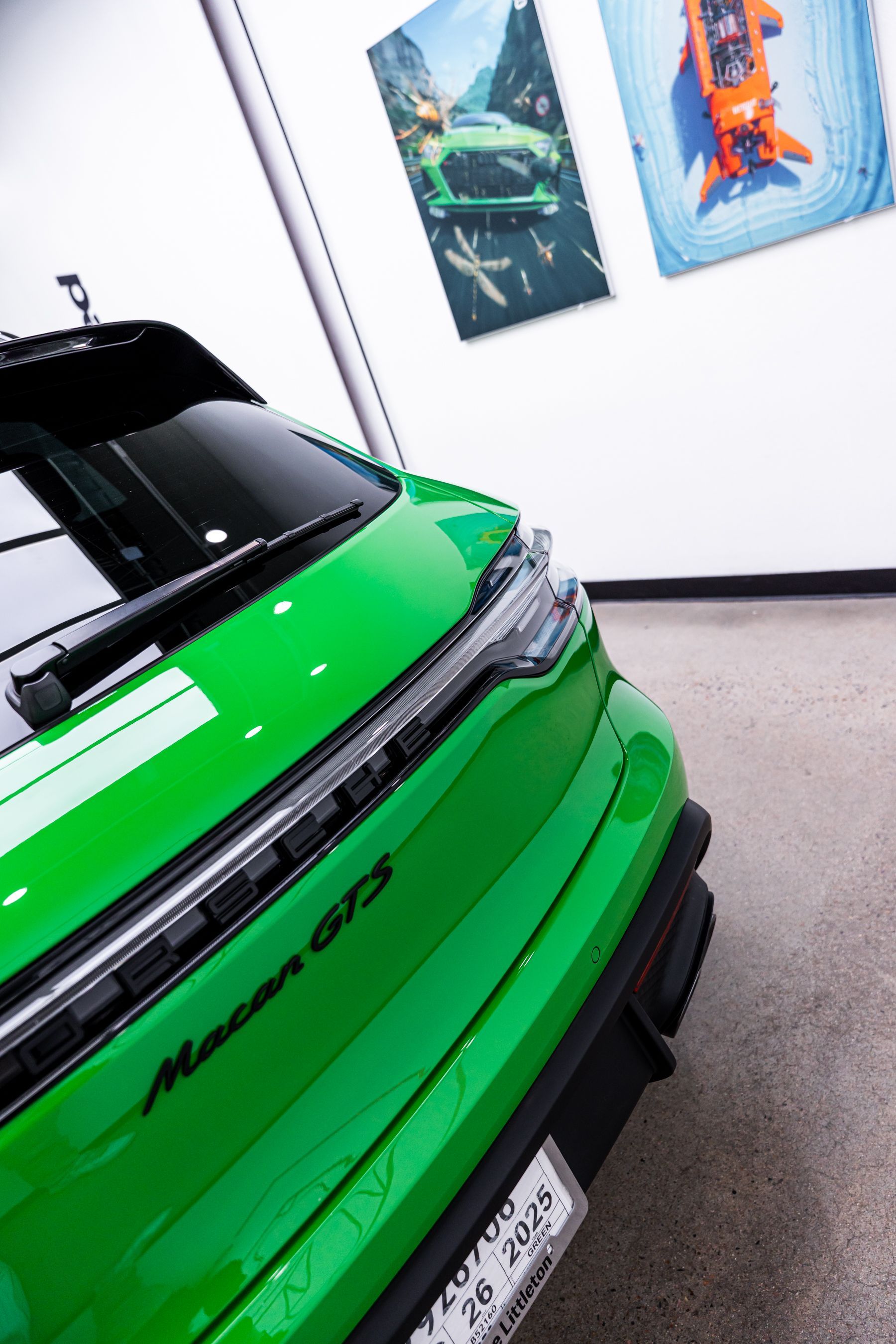 Green Porsche Macan GTS; front quarter view, parked indoors; artwork in background.