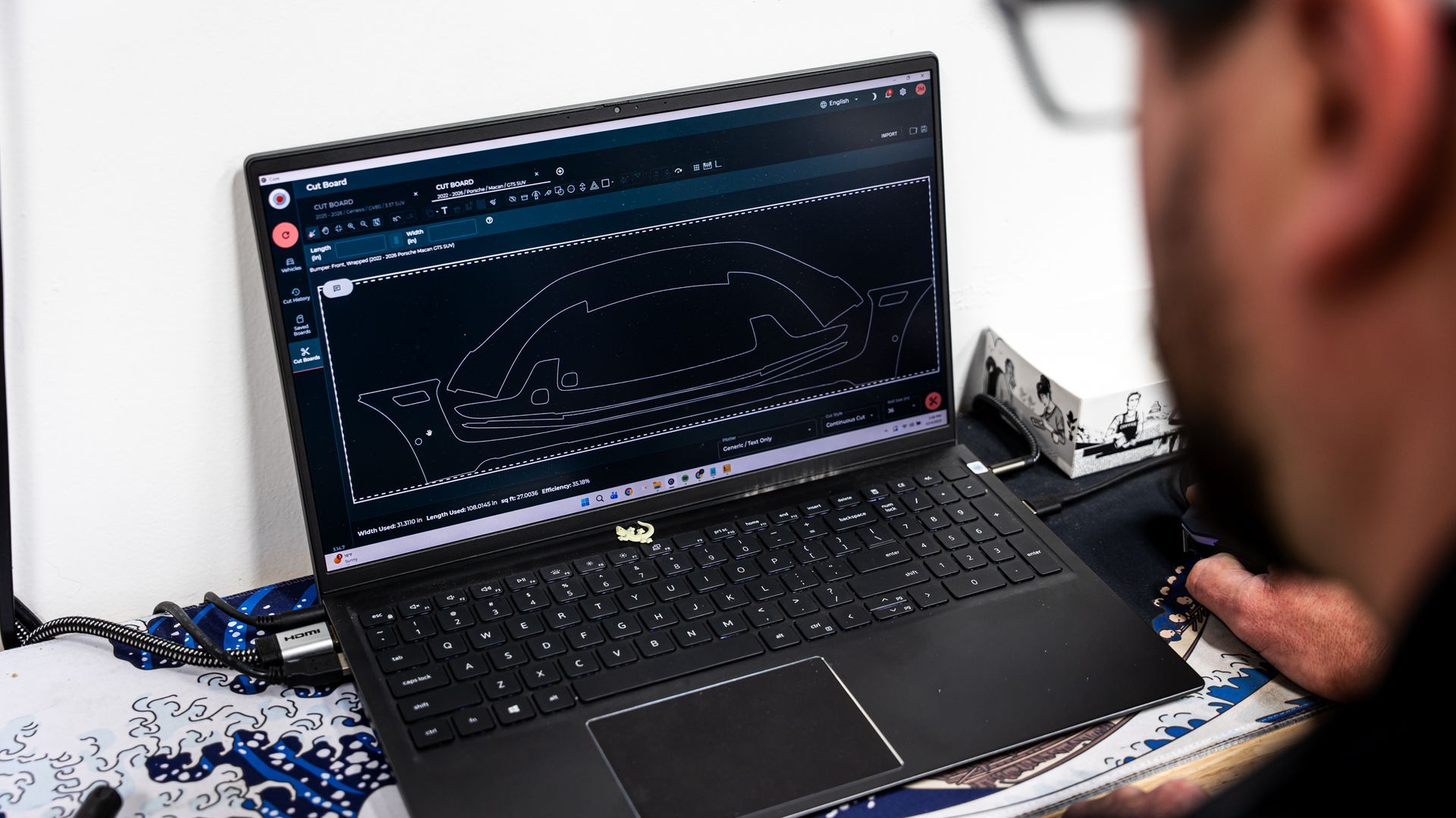 Person using a laptop displaying a technical drawing, possibly CAD software, indoors.