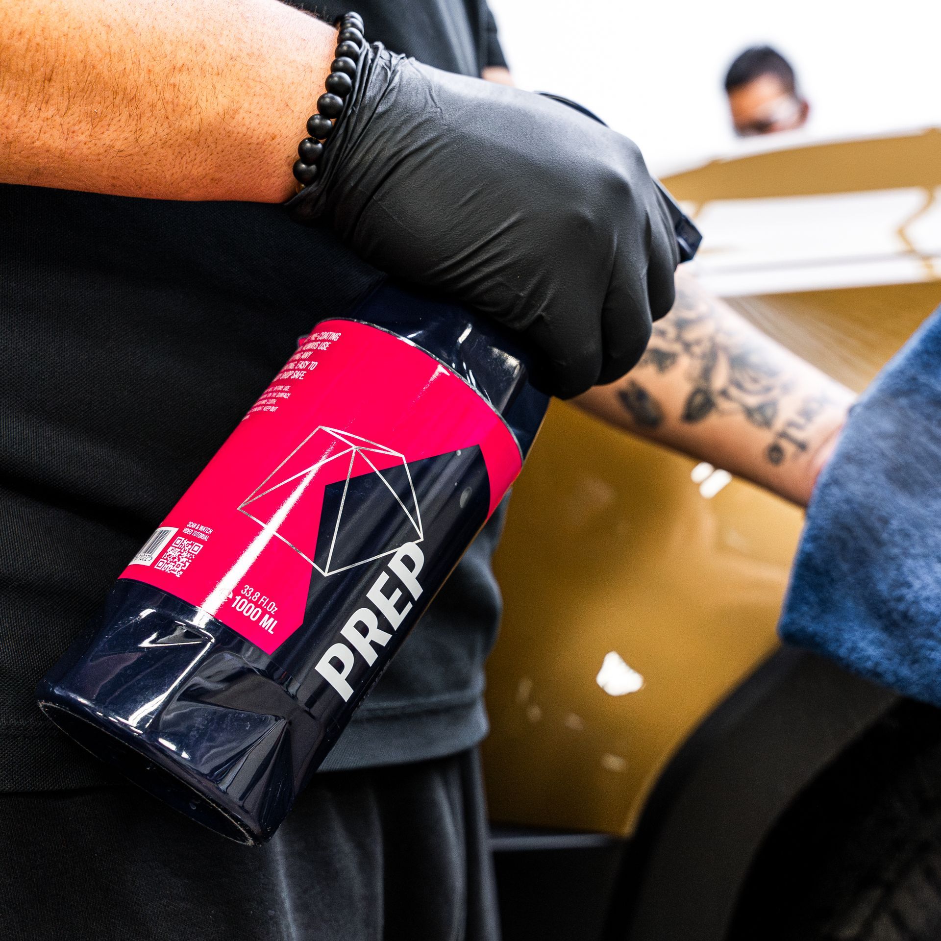 Person in black gloves spraying car with a detailing product.