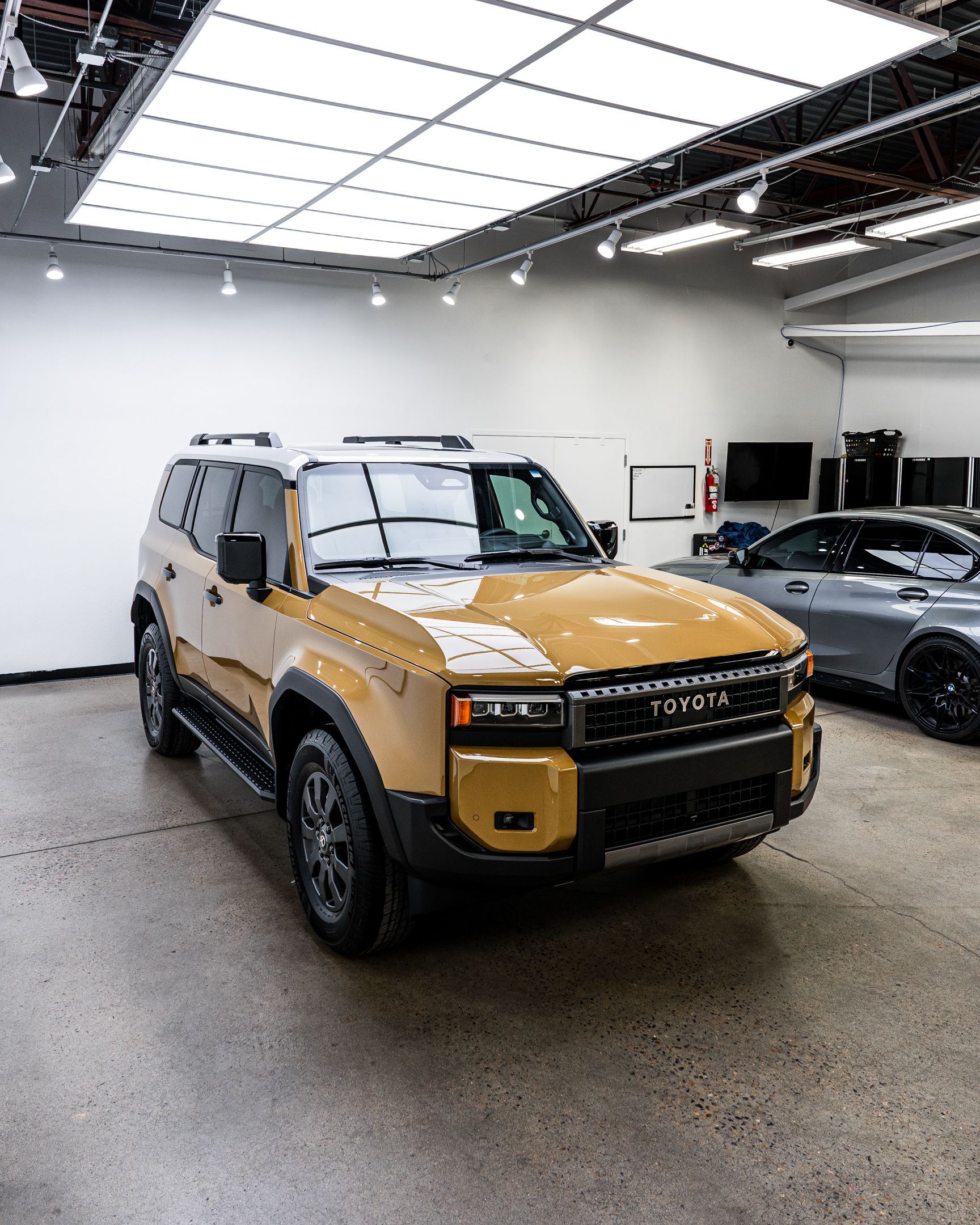 Mustard-yellow SUV parked in a showroom with gray floor and bright overhead lights.