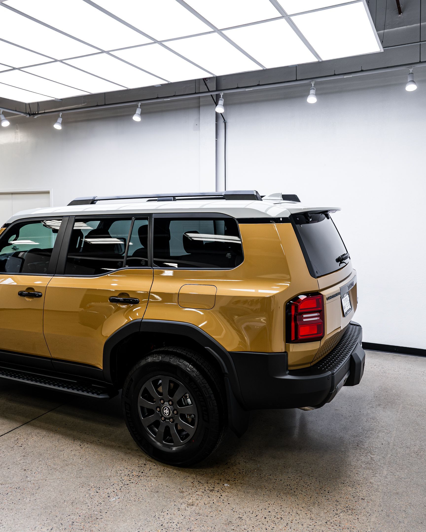 Gold Ford Bronco SUV parked indoors with a white ceiling and concrete floor.