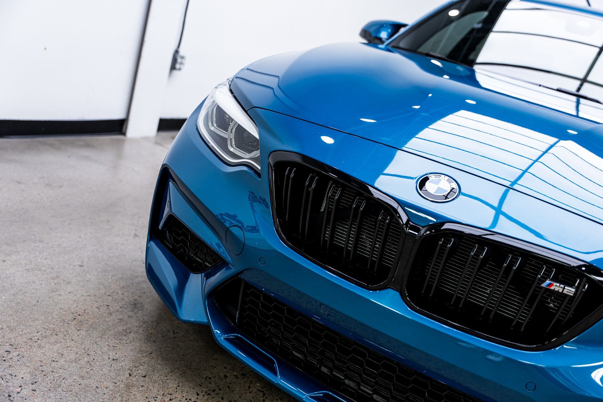 Blue BMW sports car parked indoors, shiny and reflective.