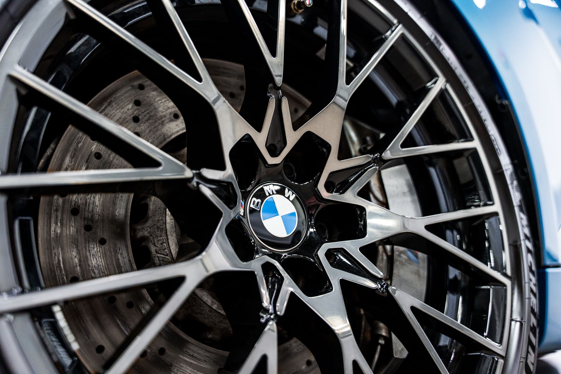 Close-up of a black and silver BMW car wheel, showing the emblem and brake disc.