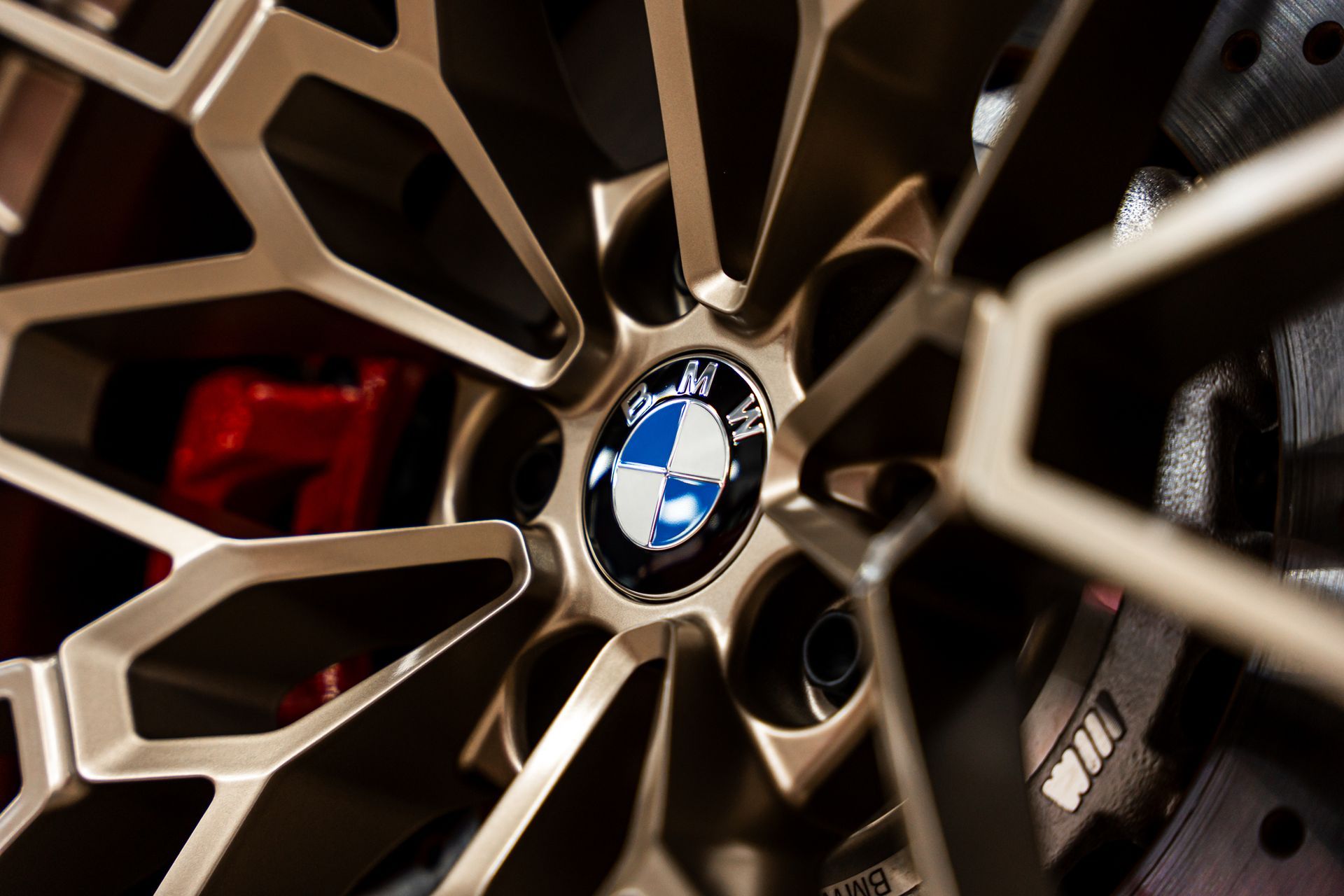 Close-up of a BMW car wheel with a bronze-colored spoke design and the BMW logo in the center.