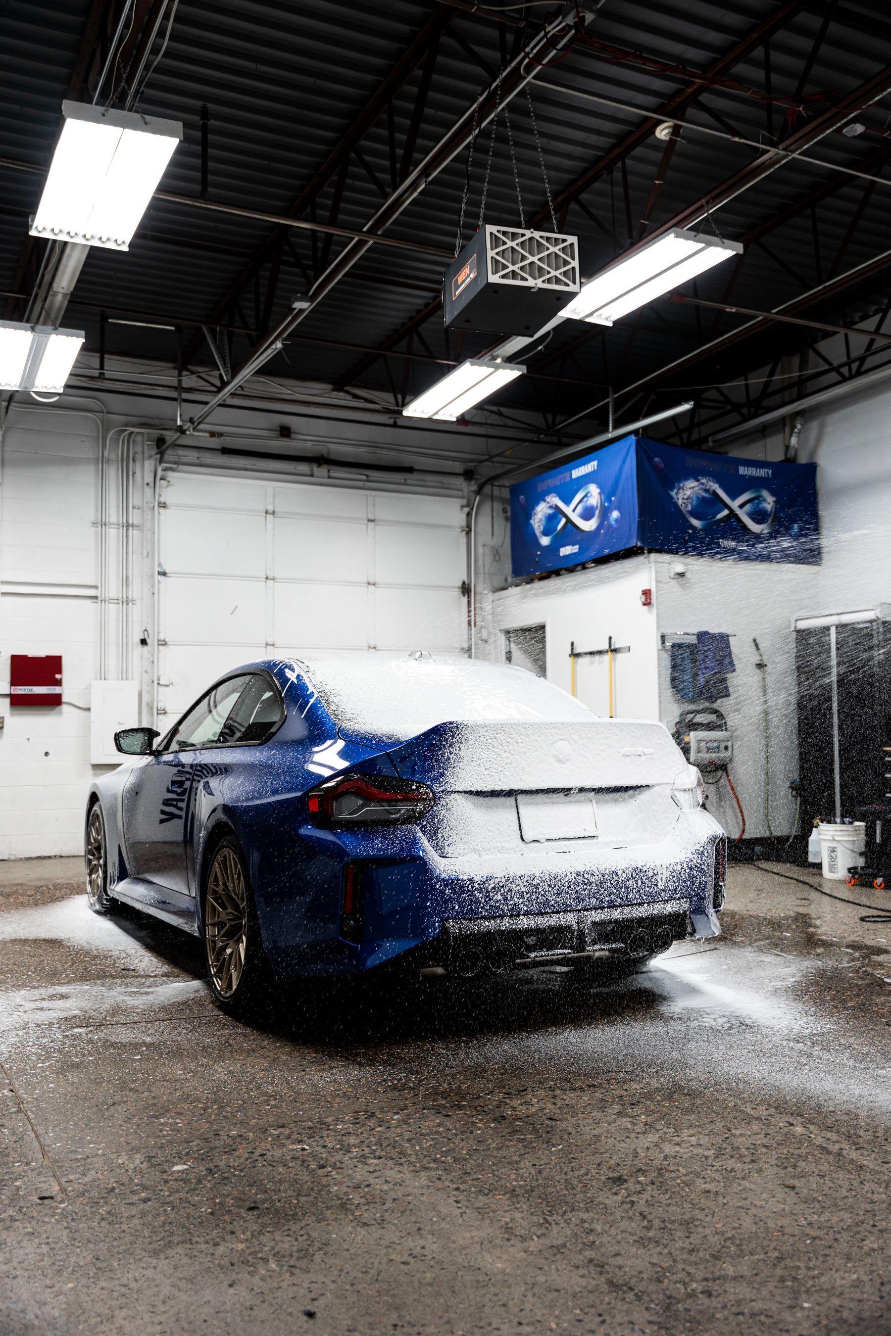 A blue car covered in foam inside a garage.