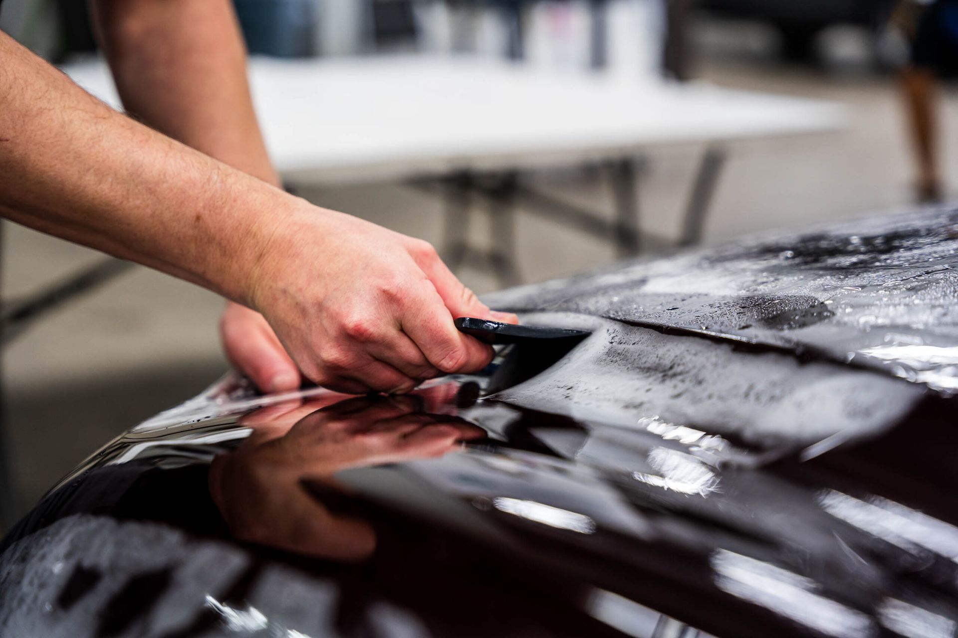 A person is cleaning the hood of a car with a brush.