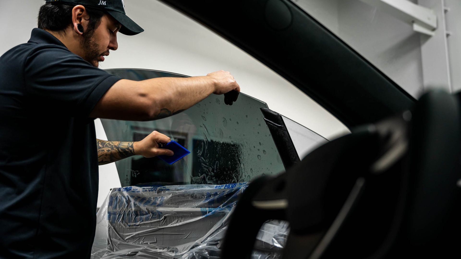 A man is applying window tinting to a car window.