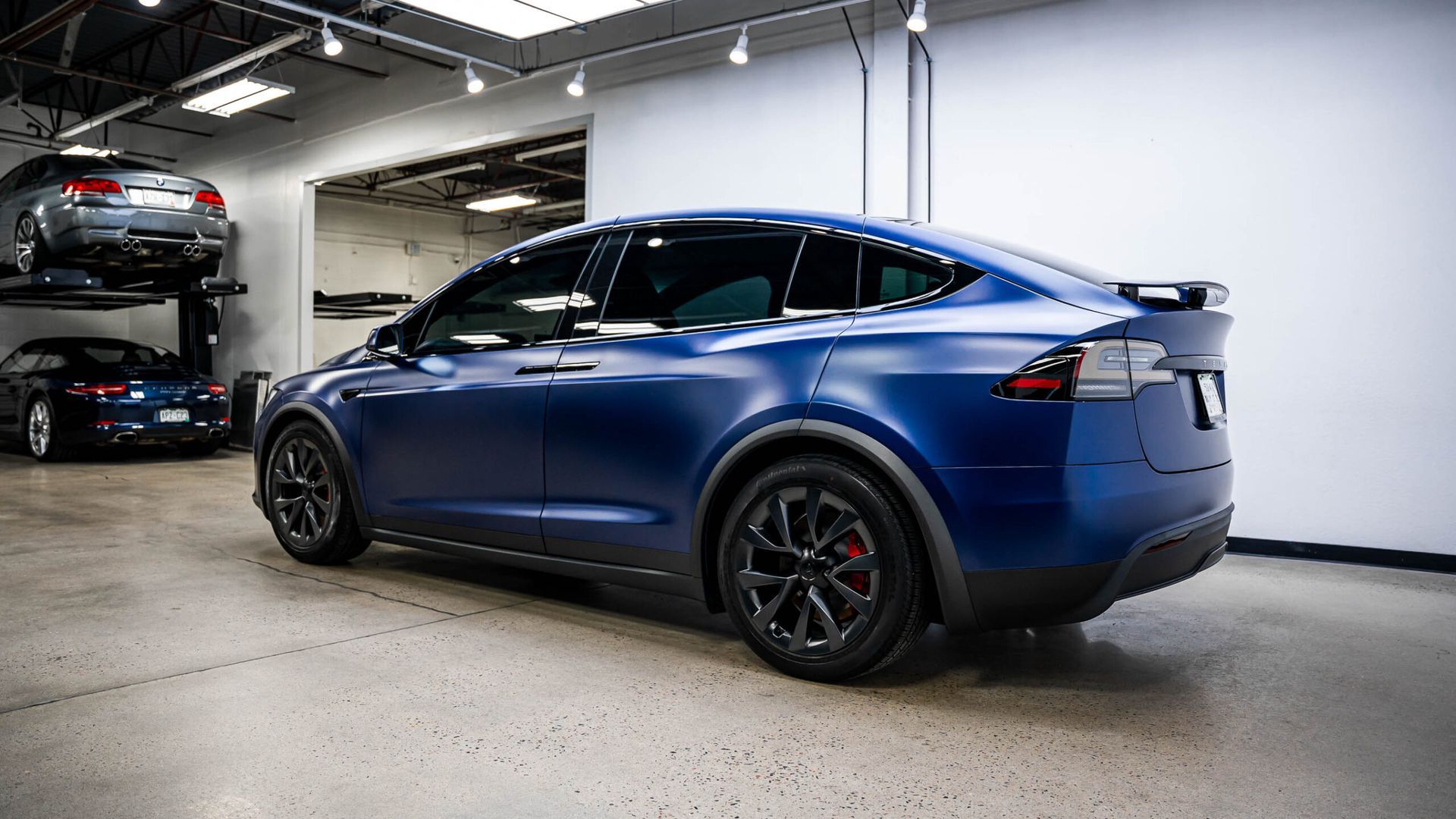 A blue tesla model x is parked in a garage.
