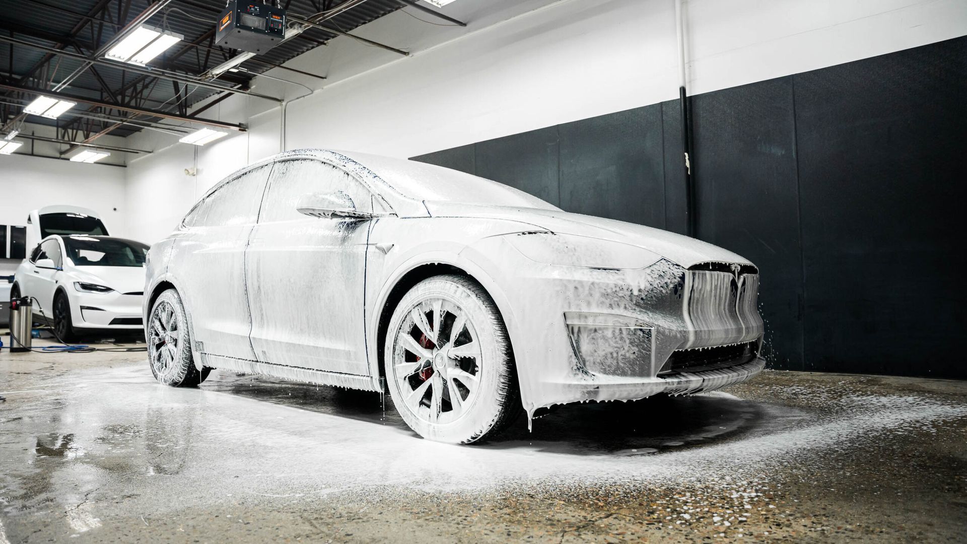 A tesla model x is covered in foam in a garage.