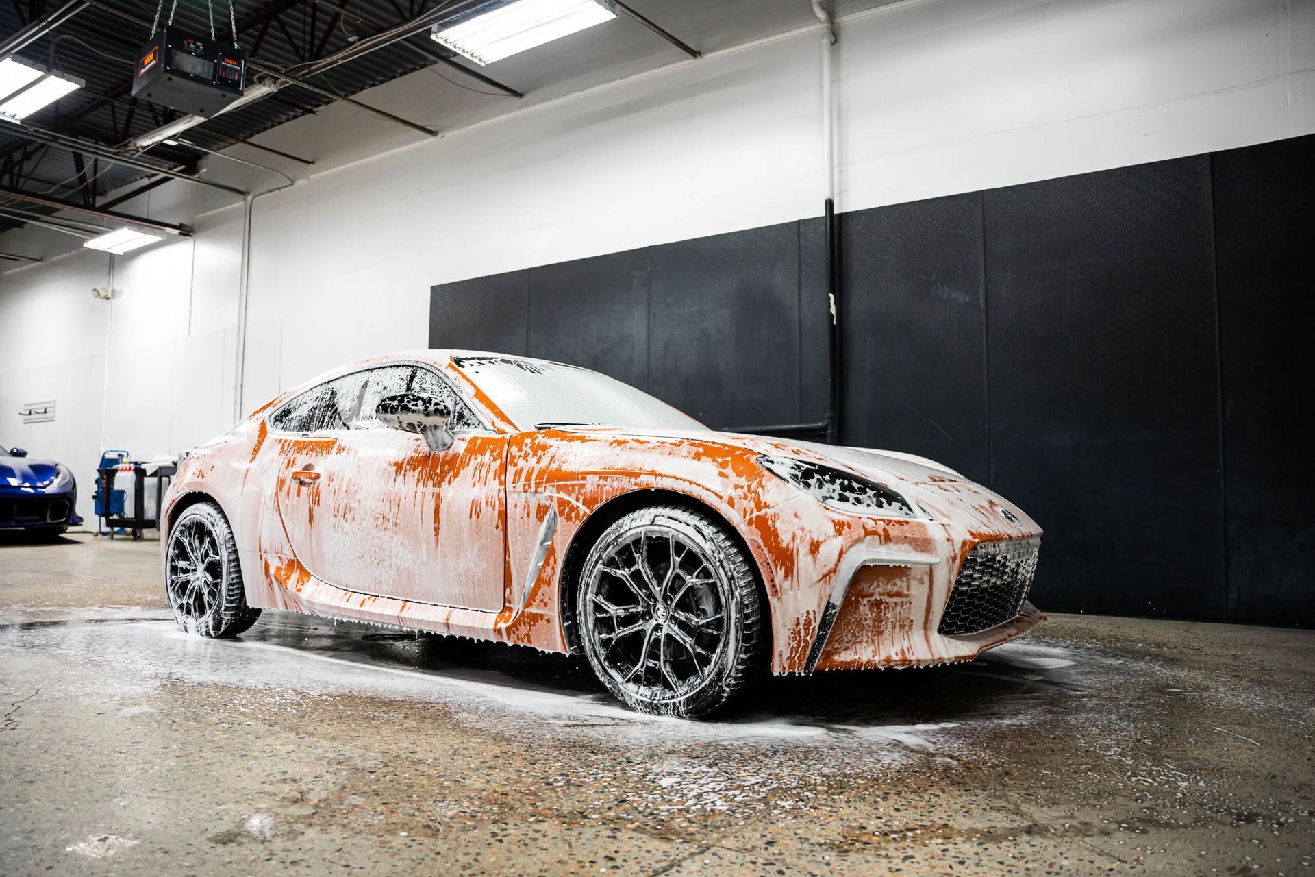 A car is covered in foam in a garage.