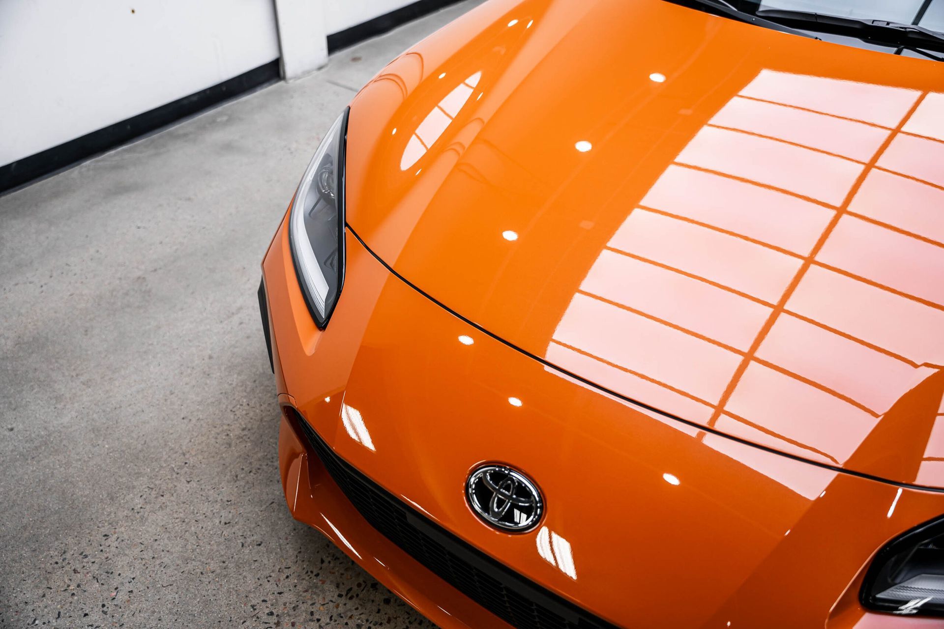 A close up of an orange car 's hood in a garage