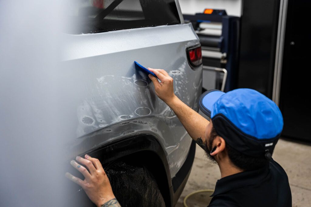 A man is cleaning the side of a truck with a sponge.