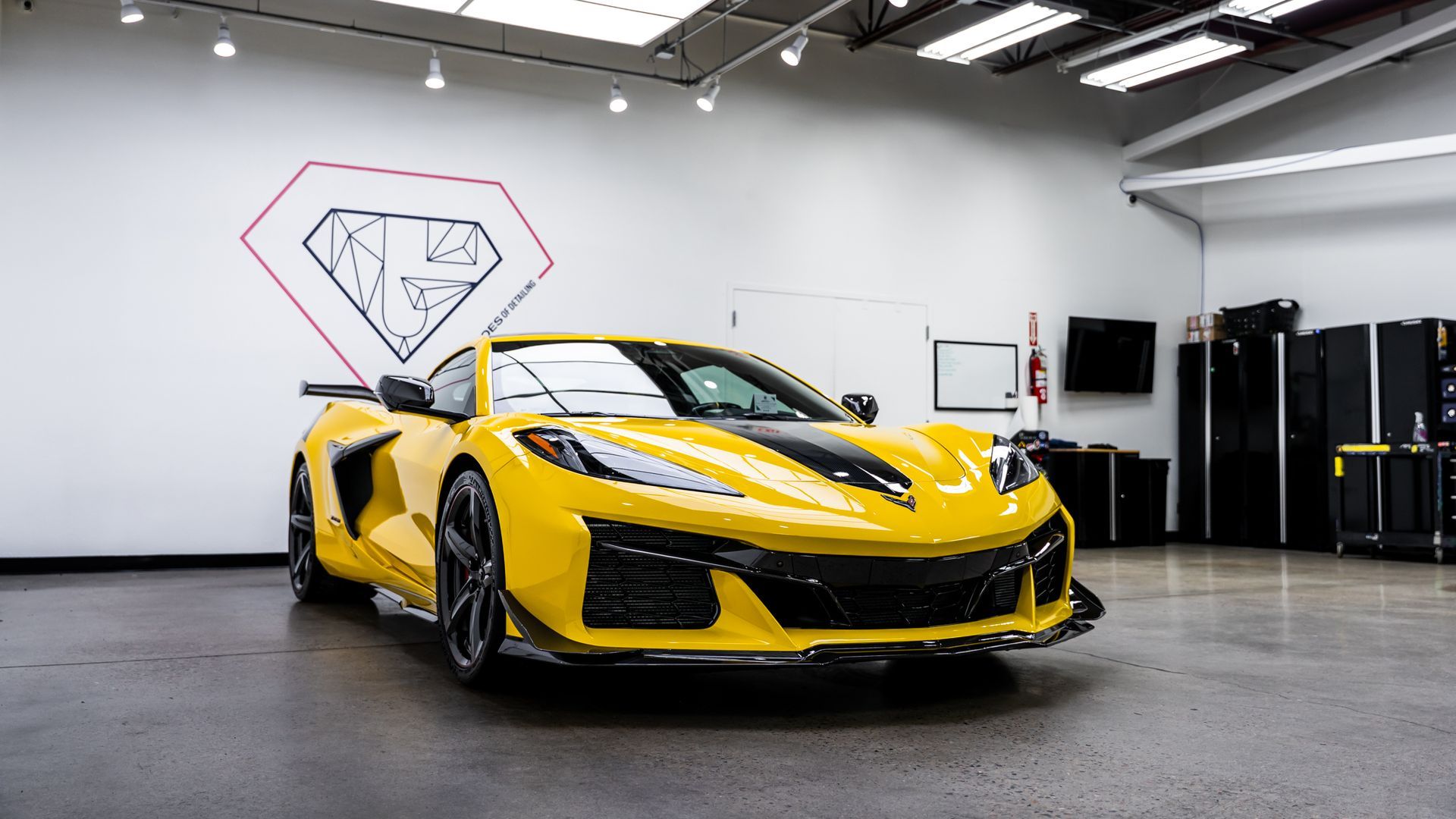 Yellow sports car with black stripe in a showroom.
