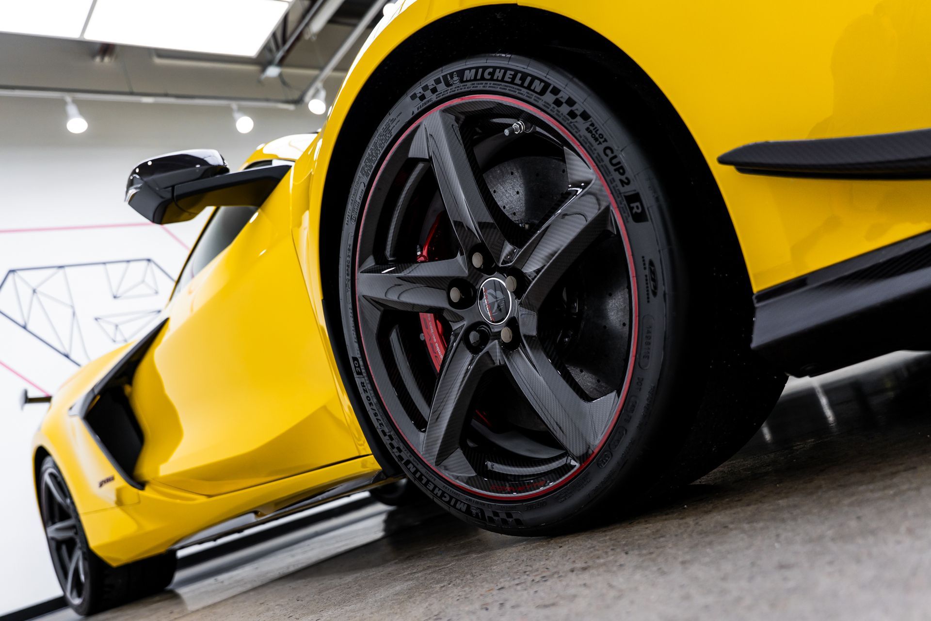 Yellow sports car with black rims and red brake calipers.