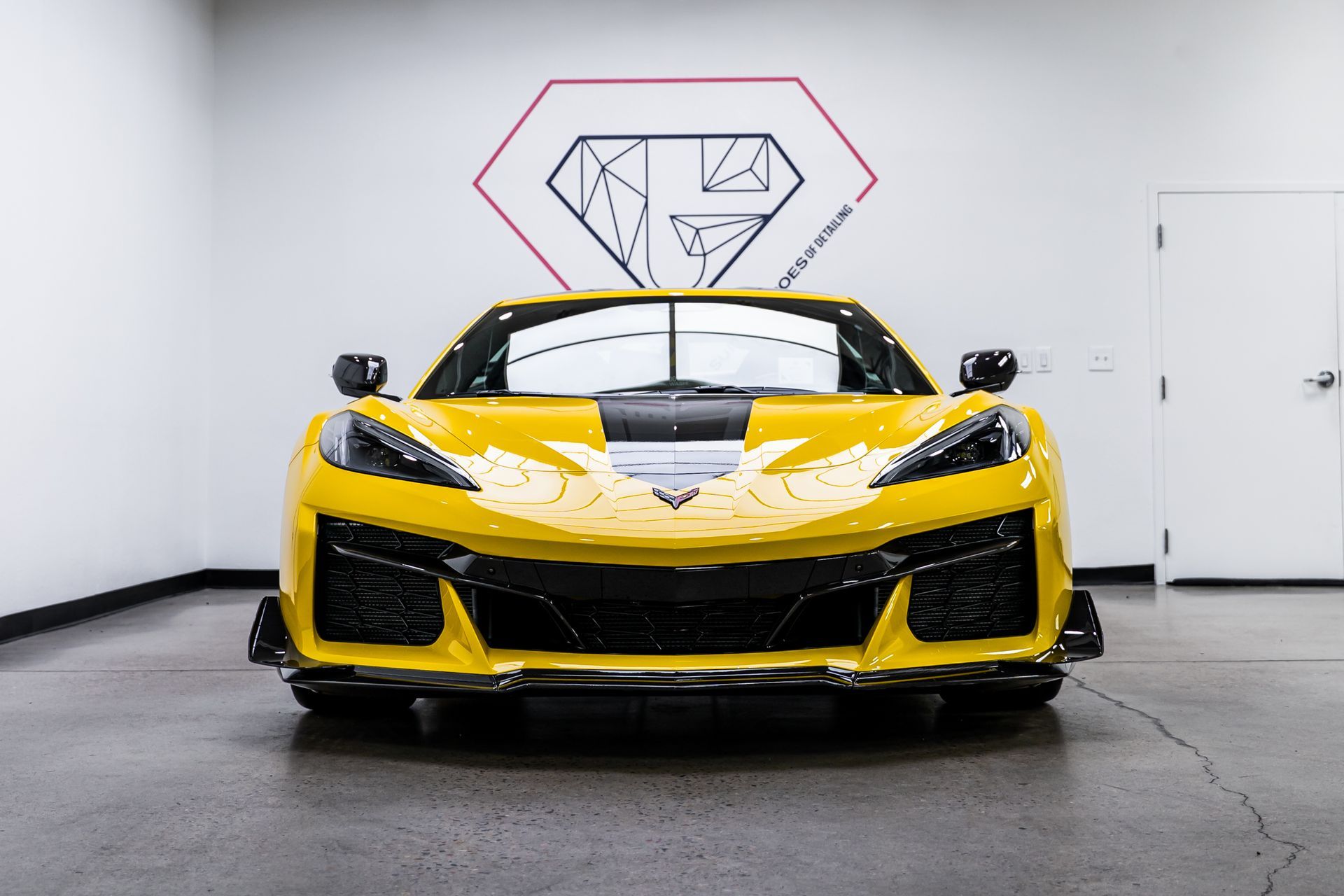 Yellow sports car with black stripe in a showroom.