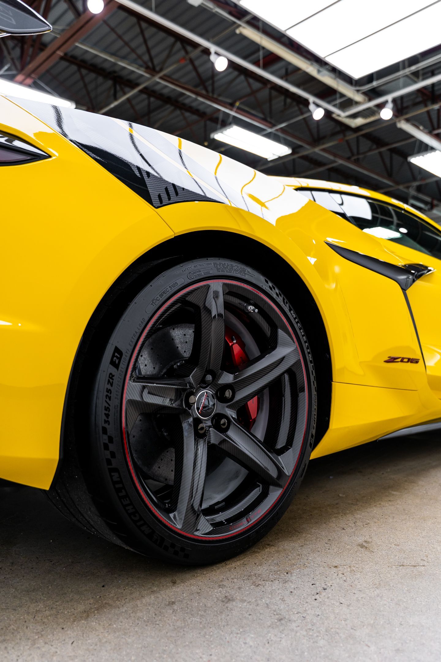 Yellow sports car with black wheels and red accents, parked indoors.