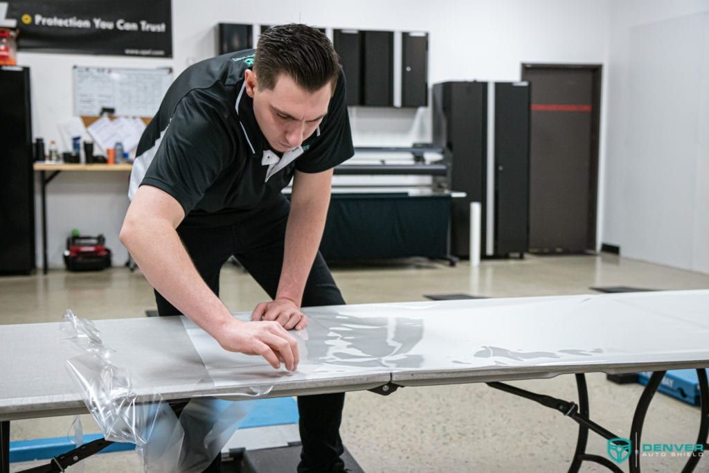 A man is covering a table with plastic wrap.