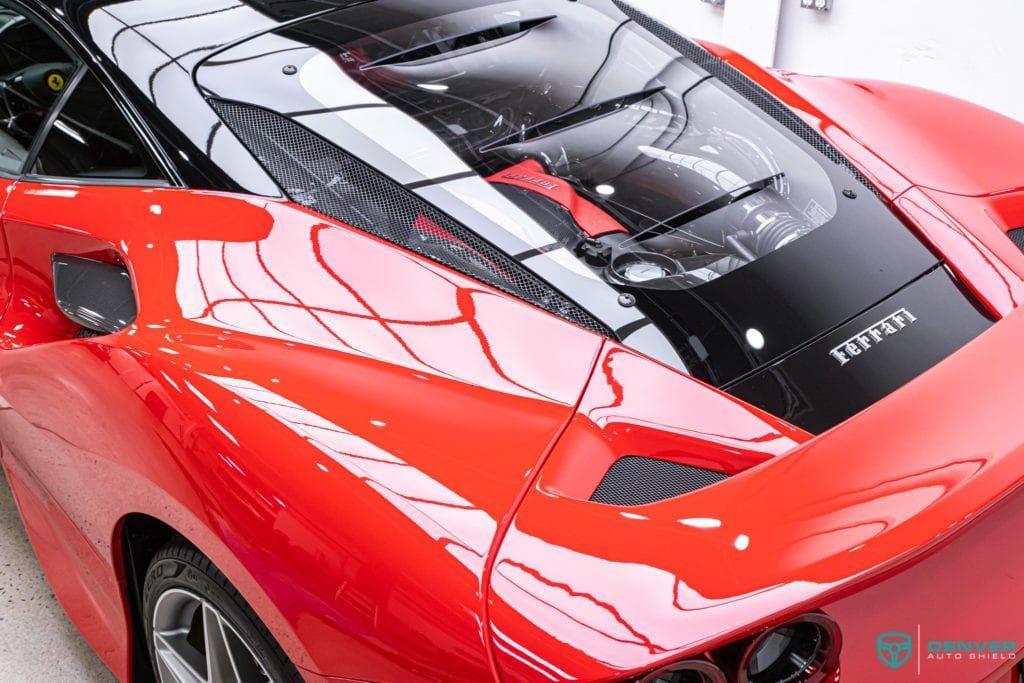 A red sports car with a black roof is parked in a garage.