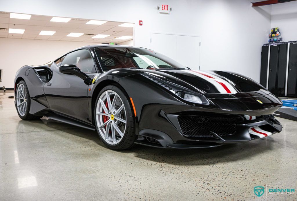 A black ferrari 488 pista is parked in a garage.