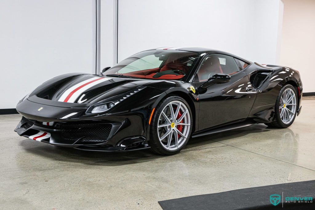 A black ferrari 488 pista is parked in a garage.