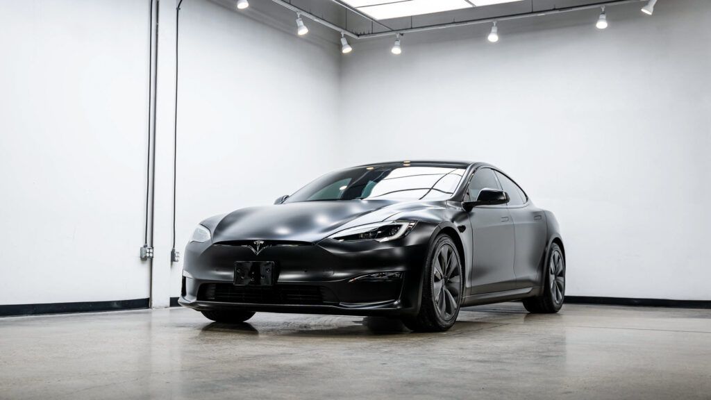 A black tesla model s is parked in a garage.