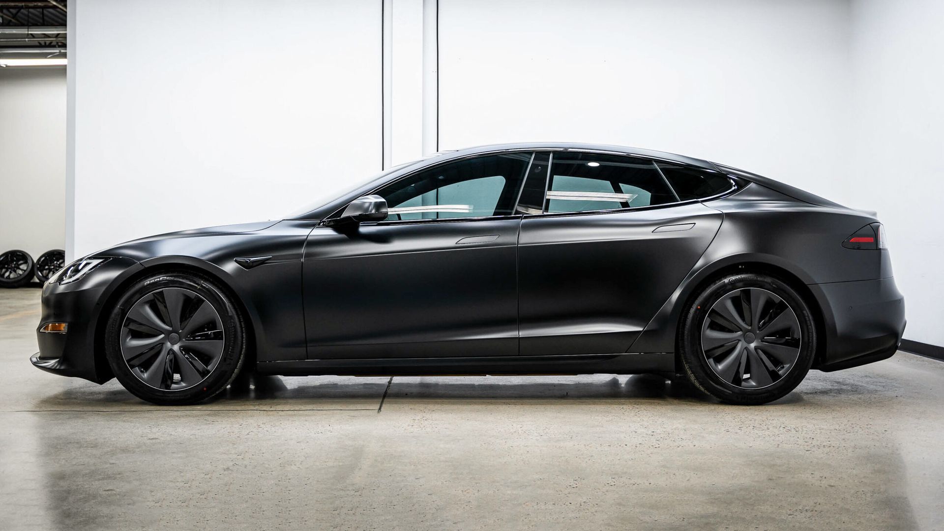 A black tesla model s is parked in a garage.