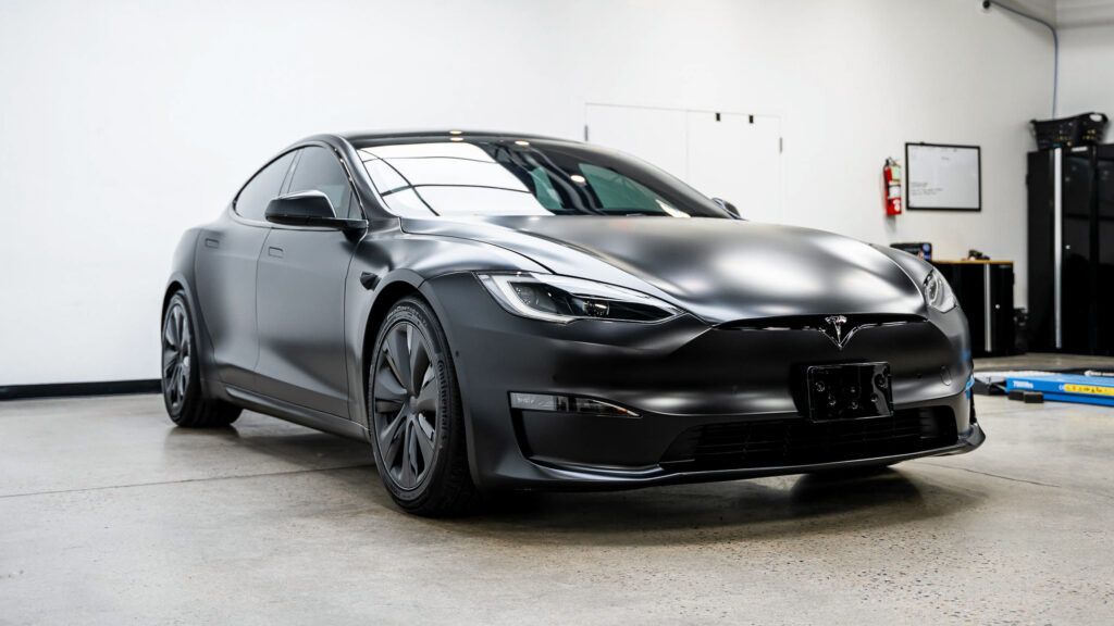 A black tesla model s is parked in a garage.