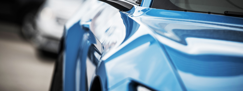 A close up of a blue car parked next to a white car.