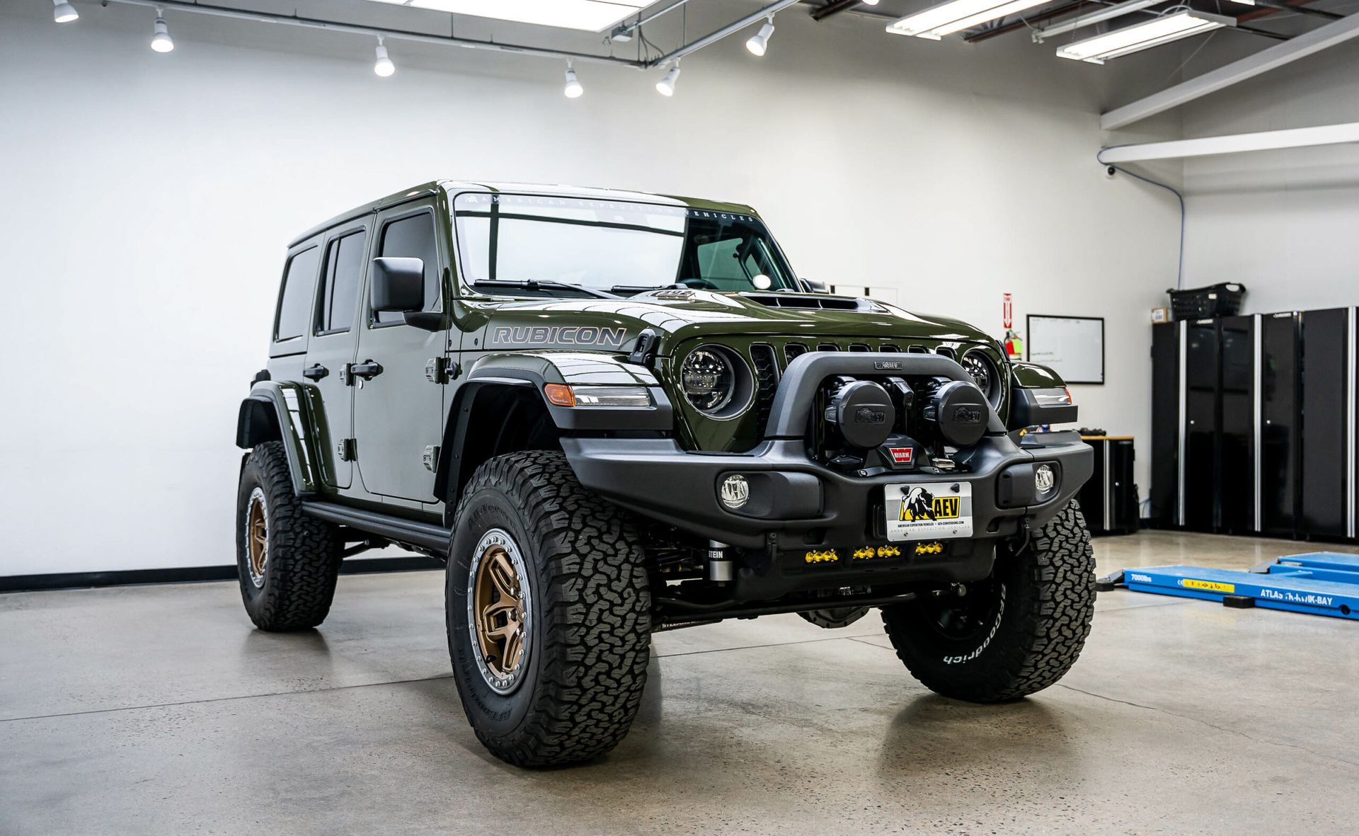 A green jeep is parked in a garage.
