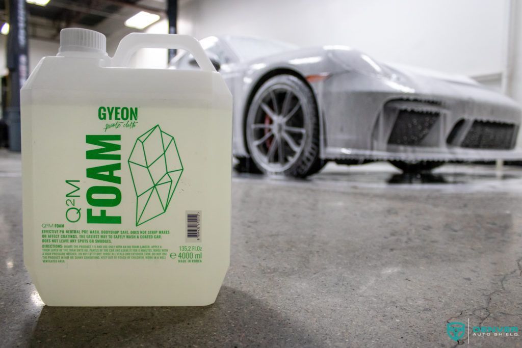 A bottle of foam is sitting next to a car in a garage.