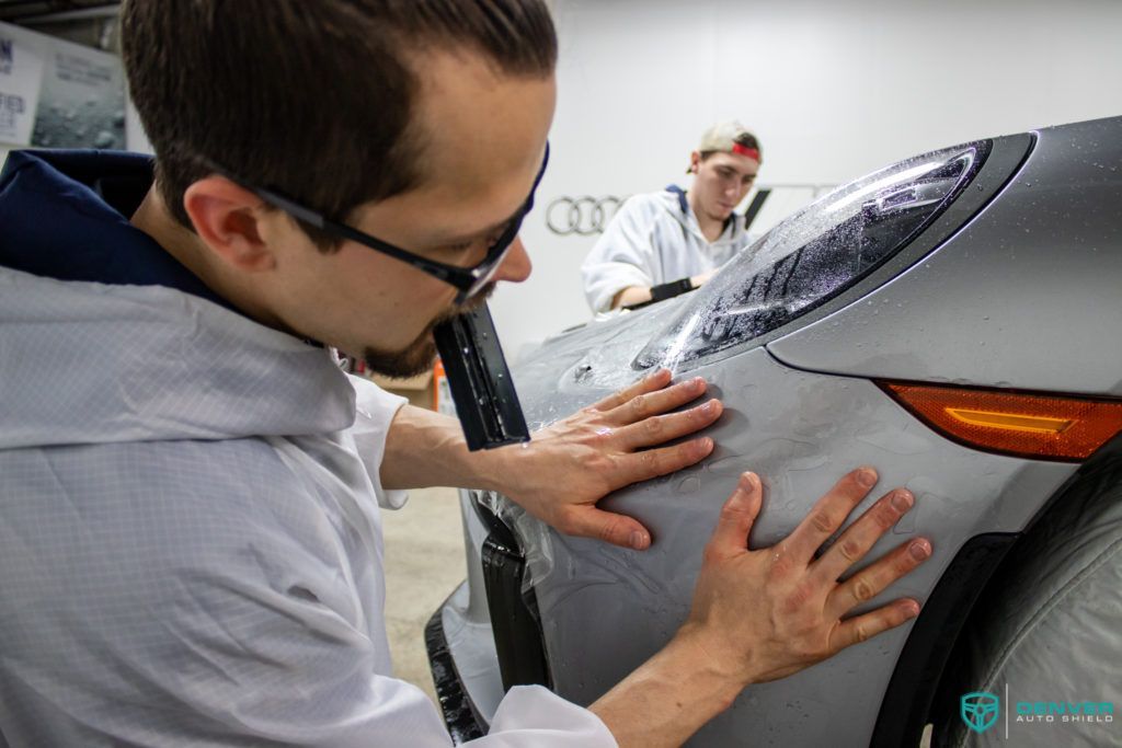 A man is wrapping a car with a protective film.
