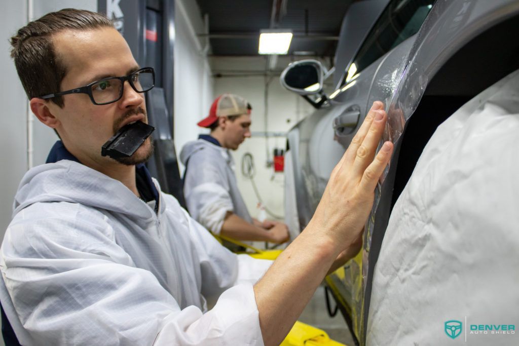 Two men are working on a car in a garage.