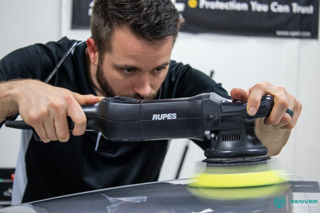 A man is polishing a car with a machine.