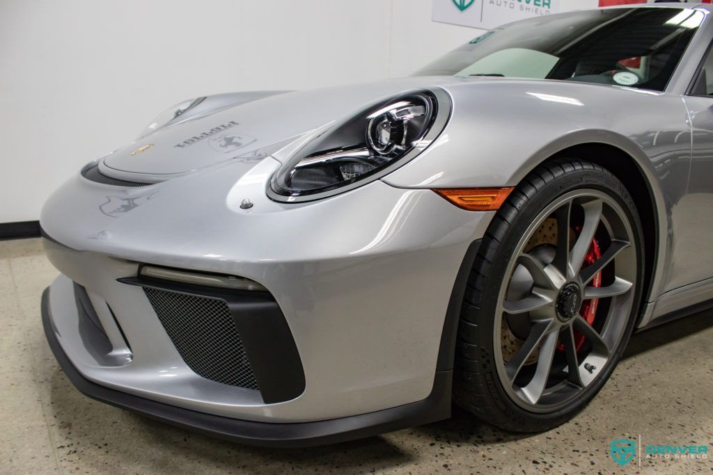 A silver porsche 911 gt3 is parked in a garage.