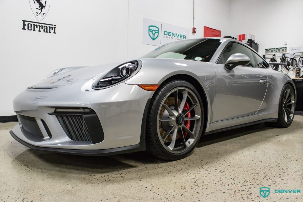 A silver porsche 911 gt3 is parked in a garage.