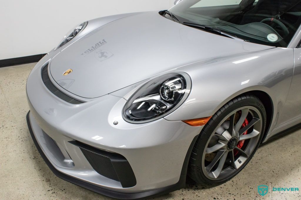 A silver porsche 911 gt3 is parked in a garage.