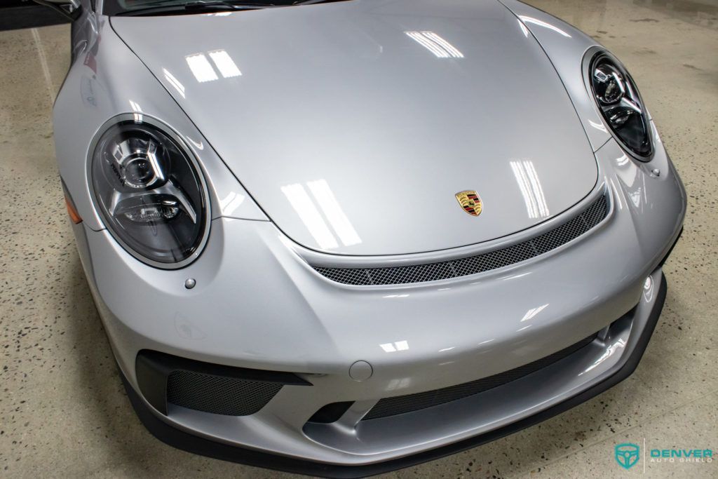 A silver porsche 911 is parked in a garage