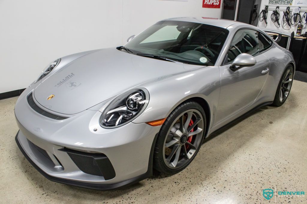A silver porsche 911 gt3 is parked in a garage.