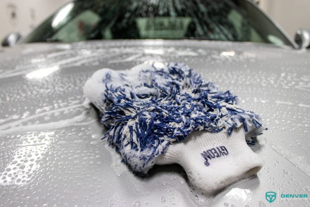 A blue and white glove is sitting on the hood of a car.