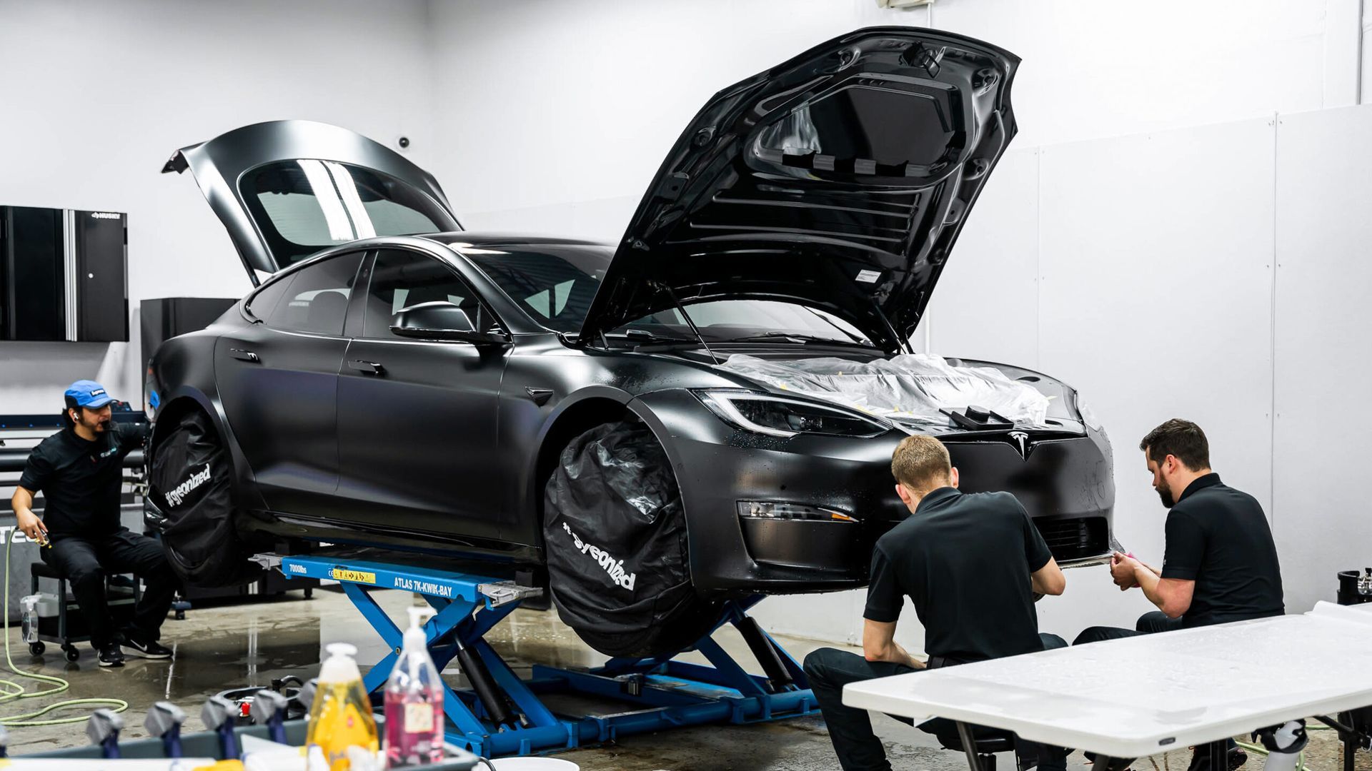 A group of men are working on a tesla model s in a garage.
