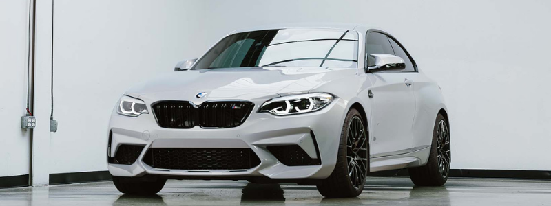 A white bmw m2 is parked in a garage.