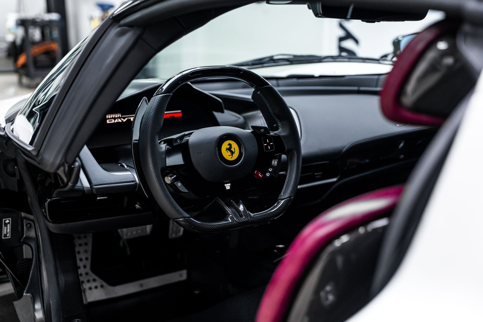 Black Ferrari interior with steering wheel and red accents.