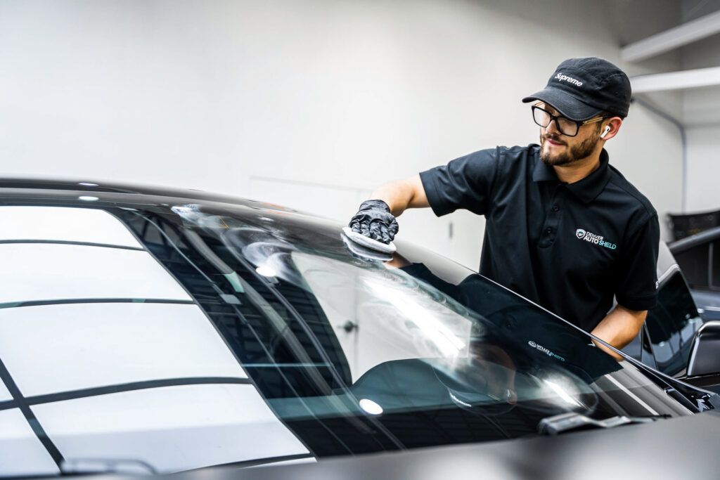 A man is cleaning the windshield of a car.