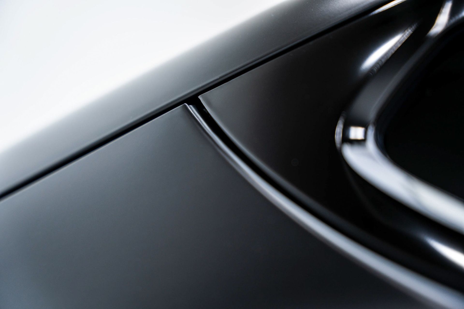 A close up of a black car with a white background.