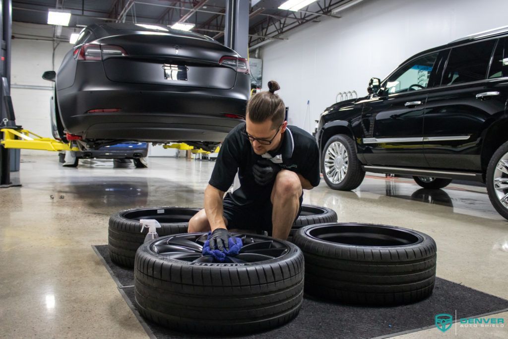 A man is working on a tesla model s in a garage.