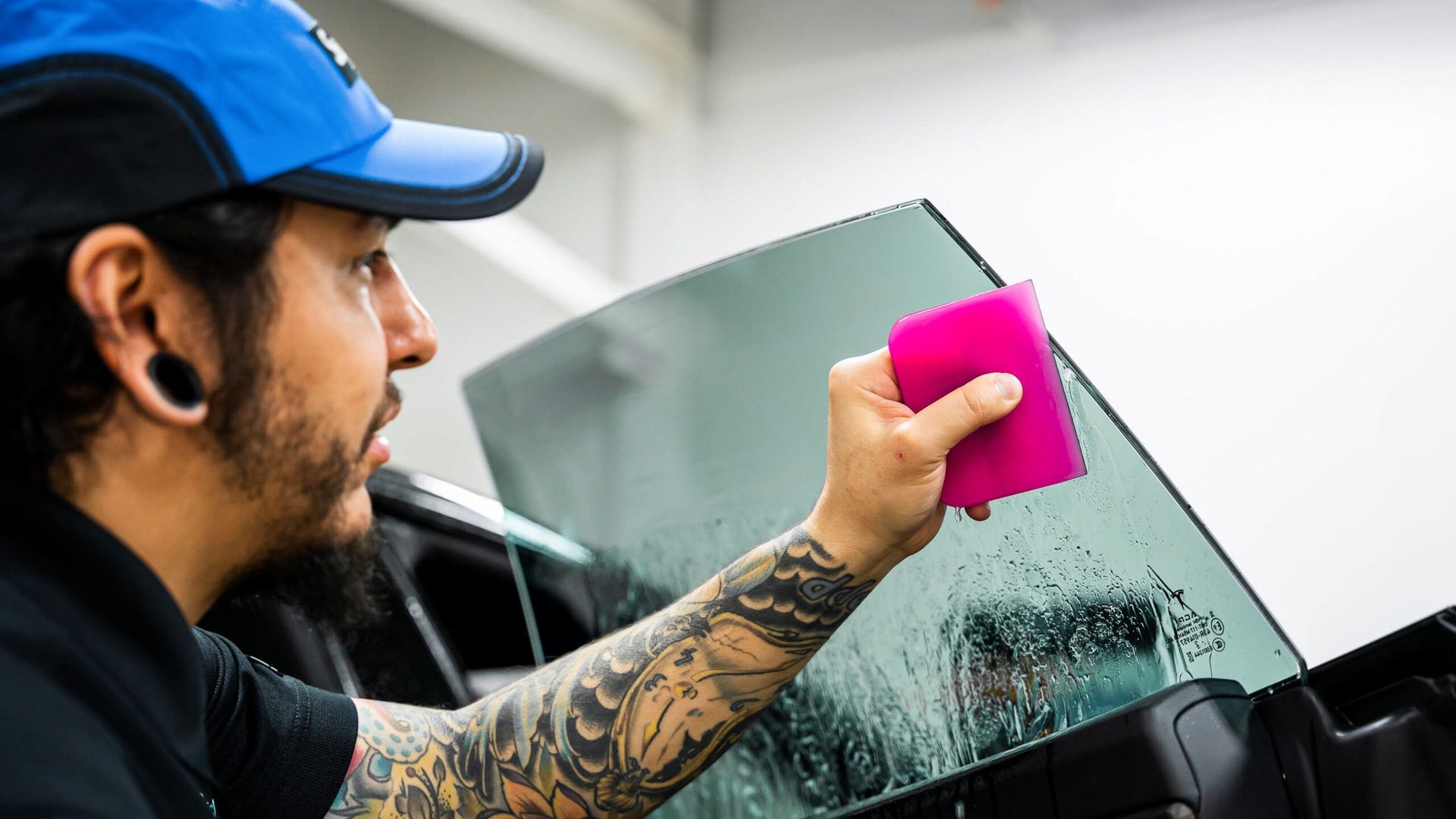 A man is applying window tinting to a car window.