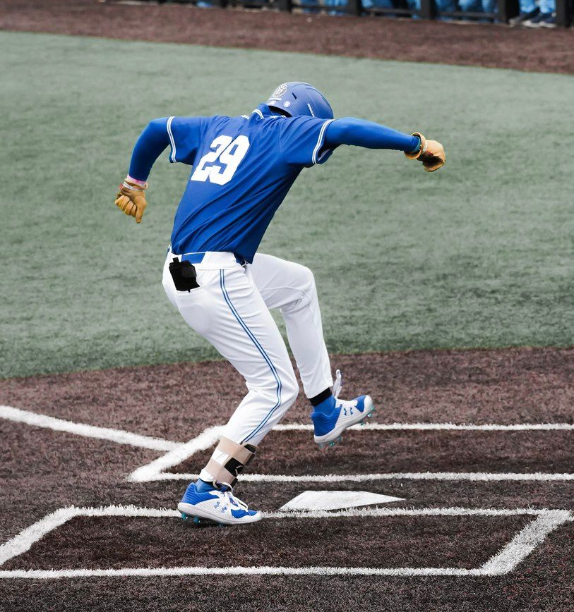 Baseball player in blue jersey stepping out of the batter’s box on the field