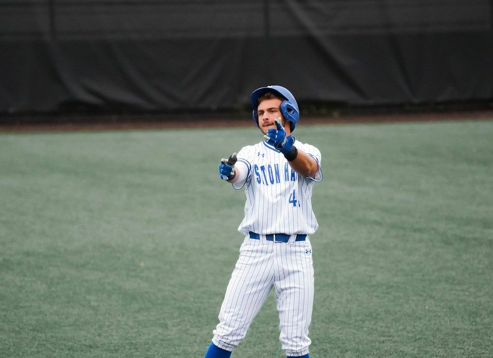 Baseball player in white and blue uniform pointing on the field