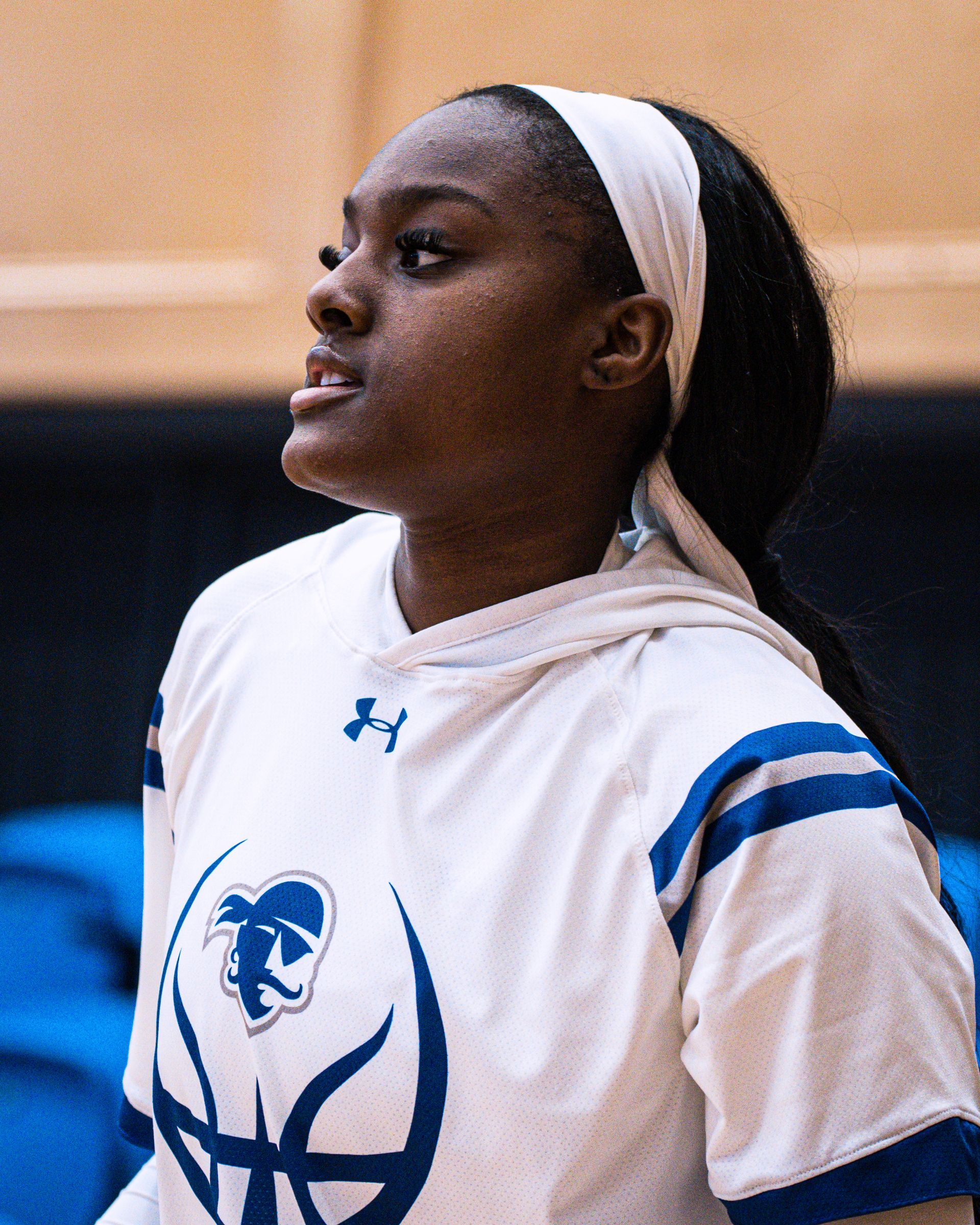 Basketball player in white hoodie jersey with blue accents, looking to the side